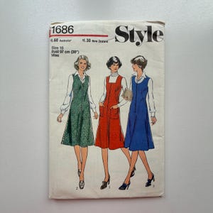 Może przedstawiać: Vintage wzór szycia "Style" z trzema wzorami sukienek. Wzór jest w rozmiarze 16, obwód biustu 97 cm. Okładka przedstawia ilustracje sukienek w kolorze zielonym, czerwonym i niebieskim, z białymi bluzkami pod spodem.