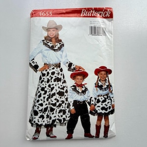 May include: A Butterick sewing pattern featuring a cowgirl costume design. The pattern includes a long skirt with a black and white cow print, a white shirt with fringe, and a cowboy hat. The pattern also includes children's cowgirl outfits.