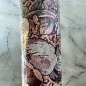 May include: A roll of floral wallpaper featuring a repeating pattern of stylized flowers and leaves in shades of pink, burgundy, and gray. The wallpaper is wrapped in clear plastic.