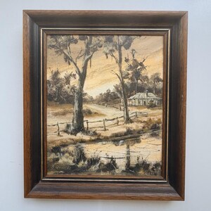 May include: An oil painting on canvas depicting a rural landscape with a small house, trees, a wooden fence, and a pond in the foreground. The artwork is rendered in shades of brown, tan, and cream, signed B. Quinn 82, and set in a dark wood frame.