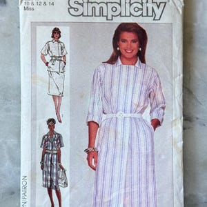 Puede incluir: Patrón de costura Simplicity 7375 para vestidos de mujer. La imagen muestra diseños de vestidos, incluido un vestido a rayas con cinturón blanco. El patrón es talla N, para tallas 10, 12 y 14.