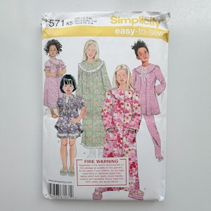 May include: A Simplicity 1571 sewing pattern envelope for children's sleepwear in sizes 7-14. The package displays illustrations of five different pyjama and nightgown styles featuring floral prints, lace trim, and button-front closures.