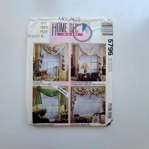 May include: A vintage McCall's Home Dec sewing pattern envelope. The front features four window treatment designs, including swags and jabots. The envelope has text that reads "Home Dec In A Sec" and "90 Minutes".