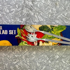 May include: A blue box with the text "2PC. SALAD SET" features a colourful salad illustration. The box contains a salad serving set with chequered handles. The salad set includes a fork and a spoon.