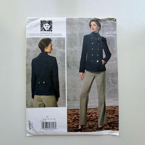May include: A sewing pattern by Anne Klein for a double-breasted jacket and pants. The pattern features a woman wearing a navy jacket with gold buttons and light brown pants. The pattern includes the Vogue Patterns American Designer logo.