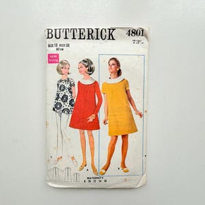 May include: A vintage Butterick 4801 sewing pattern envelope for maternity clothing. The front displays illustrations of three outfits: a black and white floral top with trousers, a solid red dress, and a solid yellow dress, all featuring white collars.