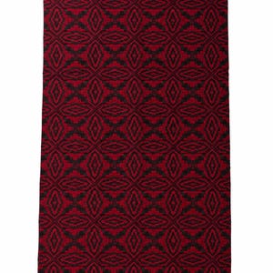 May include: A rectangular textile featuring a repeating geometric pattern in deep red and black. The design consists of interconnected diamond and lozenge shapes arranged in a grid, creating a textured appearance across the entire surface of the fabric.