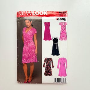 May include: New Look sewing pattern 6429 for a wrap dress. The envelope features a model wearing a pink chevron print dress and illustrations of five dress variations in solid pink, patterned pink, black, floral, and long-sleeved pink styles.