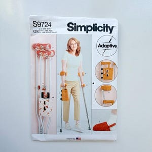 May include: Simplicity S9724 sewing pattern envelope for adaptive crutch accessories. The cover displays instructions and illustrations for creating fabric covers for crutch pads, hand grips, and a storage pouch, plus a foot cover in floral and solid fabrics.