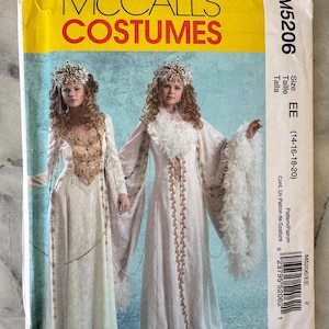 Op de afbeelding: McCall's Costumes naaipatroon M5206. Het patroon toont twee vrouwen in witte en gouden middeleeuwse jurken met gevederde mouwen en sierlijke hoofdtooien. Maat EE (42-48).