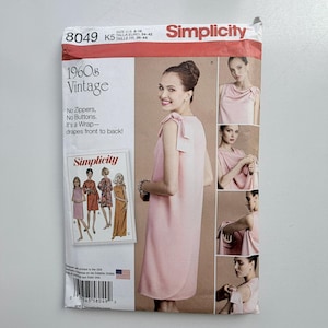 May include: A Simplicity 8049 sewing pattern envelope for a 1960s vintage wrap dress. The package features a light pink sleeveless dress with shoulder ties, text reading 1960s Vintage, No Zippers, No Buttons, and illustrations of four dress variations.