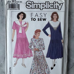 May include: A Simplicity sewing pattern packet, showing illustrations of three dress designs. The packet is white with the text "EASY TO SEW" and the pattern number 9448. The size is W5 (18-28), with EUR W5 (46-54).