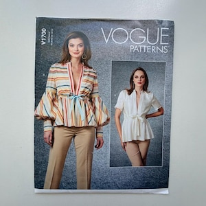 Peut inclure: Patron de couture Vogue Patterns avec une femme portant un chemisier rayé à grandes manches et un nœud bleu clair. Le patron montre également un chemisier blanc avec un nœud. Le patron est étiqueté V1700.
