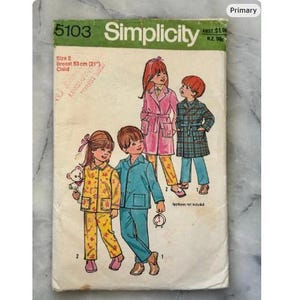 May include: Vintage Simplicity sewing pattern 5103 for children's pajamas and robes. The cover features illustrations of children in various outfits. The pattern is size 2, with a 21-inch chest measurement. The cover is aged with wear.