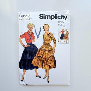 Könnte beinhalten: Ein Simplicity S9537 1950s Vintage Schnittmusterumschlag mit Illustrationen von zwei Outfits. Eines zeigt eine rote Bluse mit einem dunkelblauen Stufenrock, das andere ein gelbes Kleid mit Blumenmuster, Stufenrock und einer schwarzen Schleife.