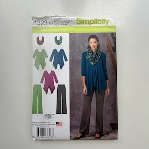 May include: Simplicity sewing pattern 1323 R5 showing a woman in a teal top and grey trousers. The pattern includes illustrations of tops and trousers in various colours. The pattern size is US 14, 16, 18, 20, 22.