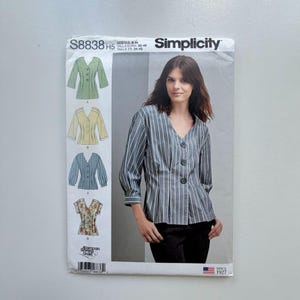 May include: Simplicity sewing pattern S8838 H5. The pattern features a woman wearing a striped blouse with a V-neck and button closure. The pattern includes illustrations of different blouse styles. The pattern is for sizes 6-14.