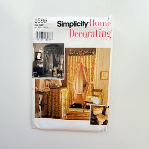 May include: A Simplicity Home Decorating sewing pattern envelope, number 9595, featuring illustrations of yellow floral curtains, a matching table skirt, and a toilet seat cover with pink ruffled trim. The white paper envelope displays text.