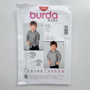 May include: A Burda Kids sewing pattern envelope, number 9505, featuring illustrations and photographs of two shirt styles, labelled A and B. The white paper envelope includes text in multiple languages, size charts from 62 to 86 and 3M to 18M, and a barcode.