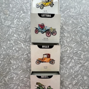 Könnte beinhalten: Ein Wandorganizer im Vintage-Stil mit vier Fächern. Jedes Fach zeigt eine klassische Autoillustration und eine Beschriftung: "LETTERS", "BILLS" und "MISC". Der obere Bereich zeigt ein Overland-Auto von 1915, der untere ein Pope Waverly von 1907.