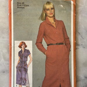 May include: Vintage Simplicity sewing pattern 9730 for a woman's dress. The envelope is orange and white, with a photo of a woman in a rust-coloured dress. Bust size is 112 cm.