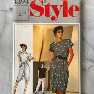 May include: Vintage Bruce Oldfield for Style sewing pattern. The cover shows a gray and white polka dot dress design, a white dress design, and a black top with white trousers. The pattern is size 12 Miss.