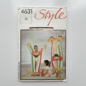 May include: A sewing pattern envelope labelled 4631 Style featuring illustrations of clown-themed costumes with vertical stripes in pastel colours. The design includes a clown face with a green hat and red hair, shown on a costume and a hanging garment bag.