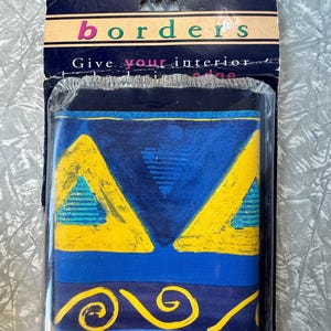 Op de afbeelding: Een pakket decoratieve randen met een blauw, geel en blauwgroen geometrisch ontwerp. De verpakking leest "borders" en "Give your interior the edge."