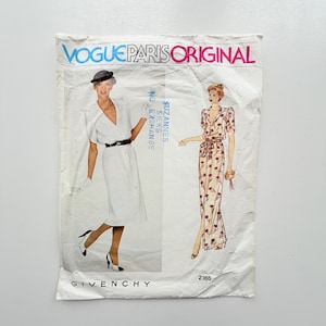 May include: A Vogue Paris Original sewing pattern envelope, number 2165, by Givenchy. The white paper envelope features a photograph of a person in a white dress and a drawing of a person in a floral print dress, with the text Vogue Paris Original.
