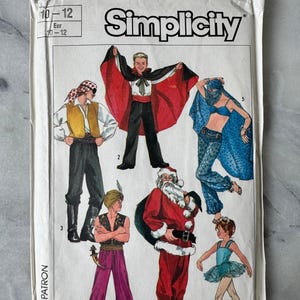 May include: Vintage Simplicity sewing pattern featuring costume designs. The cover shows illustrations of various costumes, including a pirate, a magician with a red cape, a belly dancer, Santa Claus, a genie, and a ballerina. The pattern is for sizes 10-12.