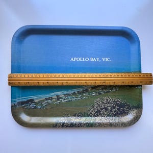 May include: A rectangular serving tray featuring a scenic coastal landscape of Apollo Bay, VIC, with a blue sky and green terrain. A wooden ruler is placed across the centre, showing the tray width is approximately 35.5 cm long.