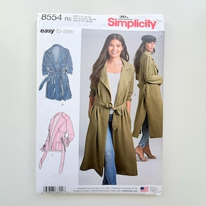 May include: Simplicity sewing pattern 8554 for a long, belted duster coat. The envelope features illustrations of a blue denim coat and a pink jacket, alongside a photograph of a model wearing an olive green version of the coat over jeans.