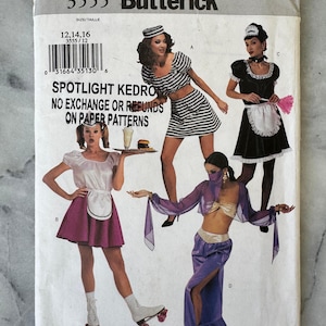 Può includere: Busta di cartamodello Butterick vintage con disegni di costumi. La copertina mostra quattro diverse idee di costumi, tra cui un abito da marinaio, una cameriera francese e una ballerina del ventre. Il testo sulla busta recita "SPOTLIGHT KEDRO" e "NO EXCHANGE OR REFUNDS ON PAPER PATTERNS."