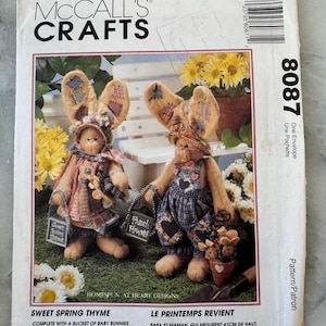May include: McCall's Crafts pattern for Sweet Spring Thyme, featuring two bunny dolls with patchwork ears and outfits. The pattern includes instructions for bunnies and clothes, with the Mom and Pop bunnies measuring 16 inches tall.