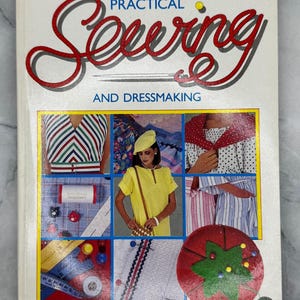 Könnte beinhalten: Buch "A Complete Guide to Practical Sewing and Dressmaking". Das Cover zeigt den Titel in roter Schrift, mit Bildern von Kleidung und Nähutensilien. Der Name des Autors, Ann Ladbury, steht unten.