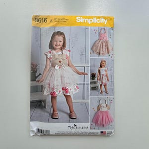 May include: Simplicity sewing pattern 8616 for girls' dresses. The pattern features a dress with a bear-shaped bodice, a floral print dress, and a pink tutu dress. The pattern is designed and printed in the USA.