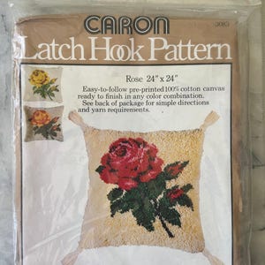 May include: A Caron Latch Hook Pattern kit with a rose design. The kit includes a 61 cm x 61 cm pre-printed cotton canvas with a red rose and green leaves. The package includes instructions and yarn requirements for the latch hook project.