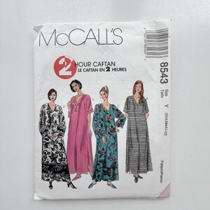 May include: A McCall's 8543 sewing pattern envelope for a 2 Hour Caftan. The white paper envelope features illustrations of four different caftan styles in black and white floral, solid pink, teal floral, and black and white striped patterns.