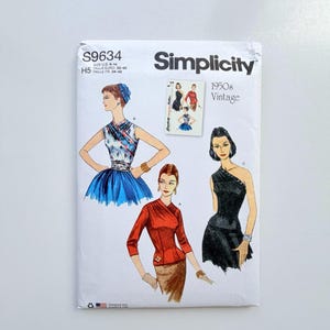 Op de afbeelding: Een Simplicity S9634 naaipatroon-envelop met vintage ontwerpen uit de jaren 50. De witte papieren hoes toont illustraties van drie verschillende outfits: een blauwe bloementop met rok, een rode top met lange mouwen met rok en een zwarte jurk.
