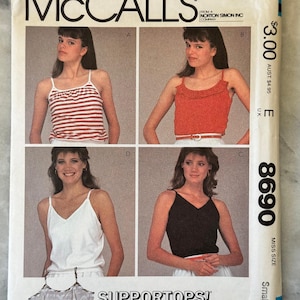 May include: McCall's sewing pattern envelope featuring four tank top designs. The designs include a red and white striped tank, a red ruffled tank, a white tank, and a black tank. The text "SUPPORTTOPS!" is visible.