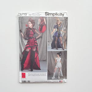 Puede incluir: Un sobre de patrón de costura Simplicity 3719, talla H5 14-22, con ilustraciones de tres diseños de disfraces distintos. Las imágenes muestran un vestido rojo y negro con dobladillo alto, un traje de bruja azul y negro y un conjunto blanco.