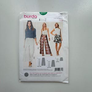 May include: A Burda Style sewing pattern envelope, showing three garment designs: wide-leg trousers, palazzo trousers, and a skirt. The envelope is white with the Burda Style logo and the number 6771. The designs are shown on models.