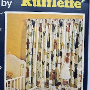 May include: A product box for Rufflelette curtains featuring a cream-colored fabric with a repeating pattern of stylized animals including cats, dogs, and birds. The box displays a nursery scene with a crib, a table lamp, and baby accessories.