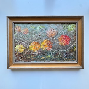 May include: An oil painting in a rectangular wooden frame featuring a textured, impasto-style floral scene with vibrant red, orange, and yellow blossoms against a muted green background. The signature G. JODELL 70 is visible in the bottom right corner.