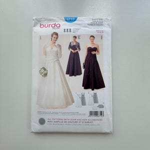 May include: A Burda Style sewing pattern for a dress and jacket, number 6710. The cover features illustrations of three different dress styles, including a strapless gown and a dress with a jacket. The pattern includes seam and hem allowances.