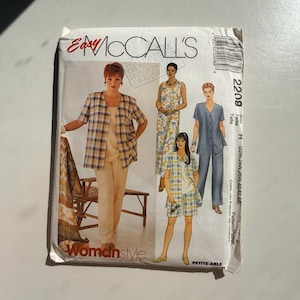 May include: A vintage McCall's sewing pattern titled "Womanstyle." The pattern features illustrations of women's clothing, including a plaid shirt and pants, a floral jumpsuit, and a denim pantsuit. The pattern size is H (22W, 24W, 26W, 40, 42, 44).