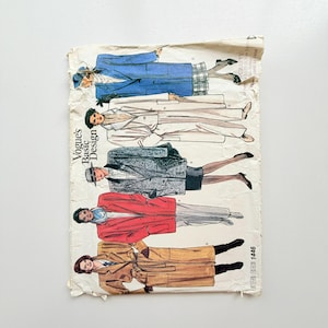 Peut inclure: Une pochette de patron de couture Vogue Basic Design, numéro 1446, présentant des illustrations de cinq styles différents de manteaux et vestes en bleu, blanc, gris, rouge et beige. L'enveloppe en papier est usée et comporte du texte imprimé.