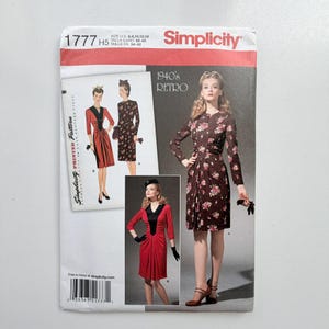 May include: A Simplicity 1777 sewing pattern envelope for a 1940s style dress. The cover features illustrations and photographs of two dress variations: one in a brown floral print and one in solid red with a black V-neck panel and long sleeves.