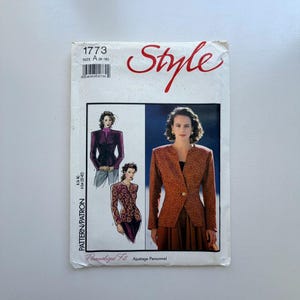 May include: A vintage sewing pattern titled "Style" with the number 1773. The cover features illustrations of a woman wearing a jacket and skirt. The jacket is a reddish-brown color with a floral pattern. The pattern size is A (6-16).