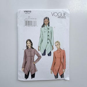 May include: Vogue Patterns V9212 sewing pattern envelope featuring three illustrations of a jacket with an asymmetrical front closure, high collar, and long sleeves. The pattern is size E5, covering sizes 14, 16, 18, 20, and 22. The jacket designs are shown in light green, coral, and a dark patterned fabric.